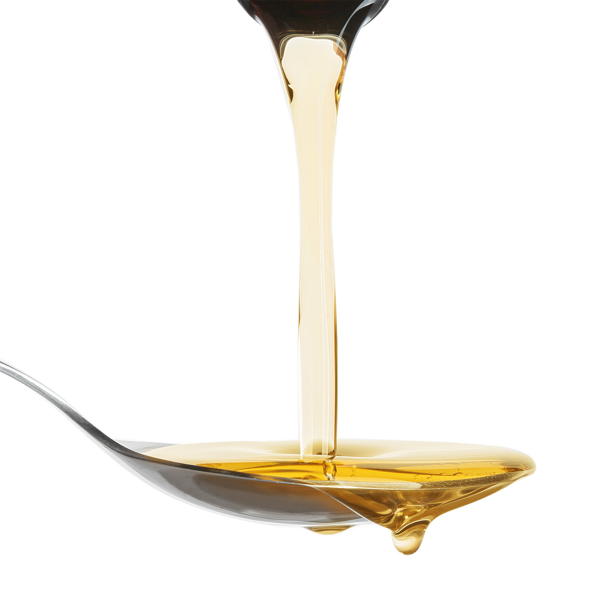 Golden amber liquid shown dripping from a dark container onto a silver spoon against a solid white background.