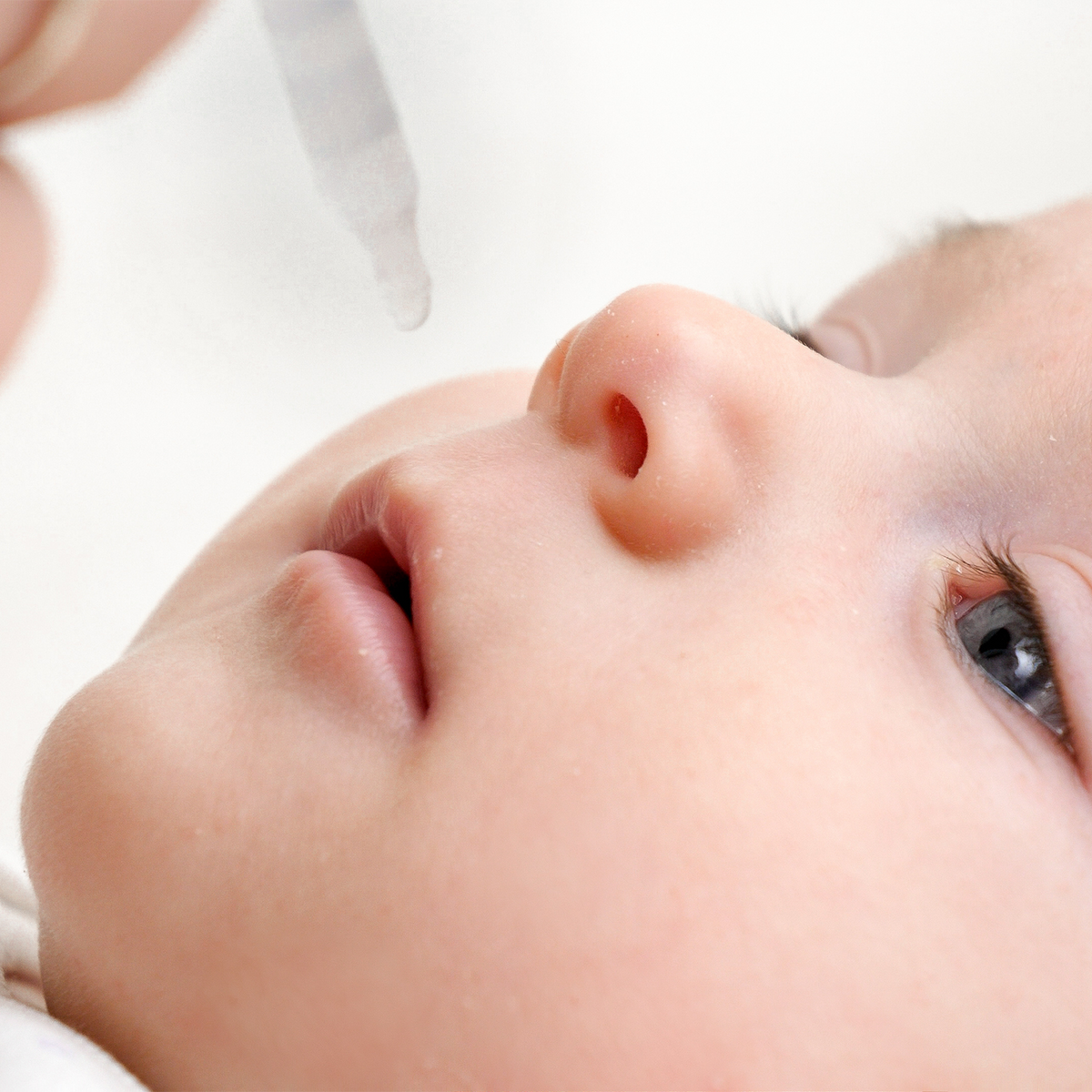 Close-up of a baby's face with a dropper above the nose, suggesting a pediatric liquid product or medicine application.