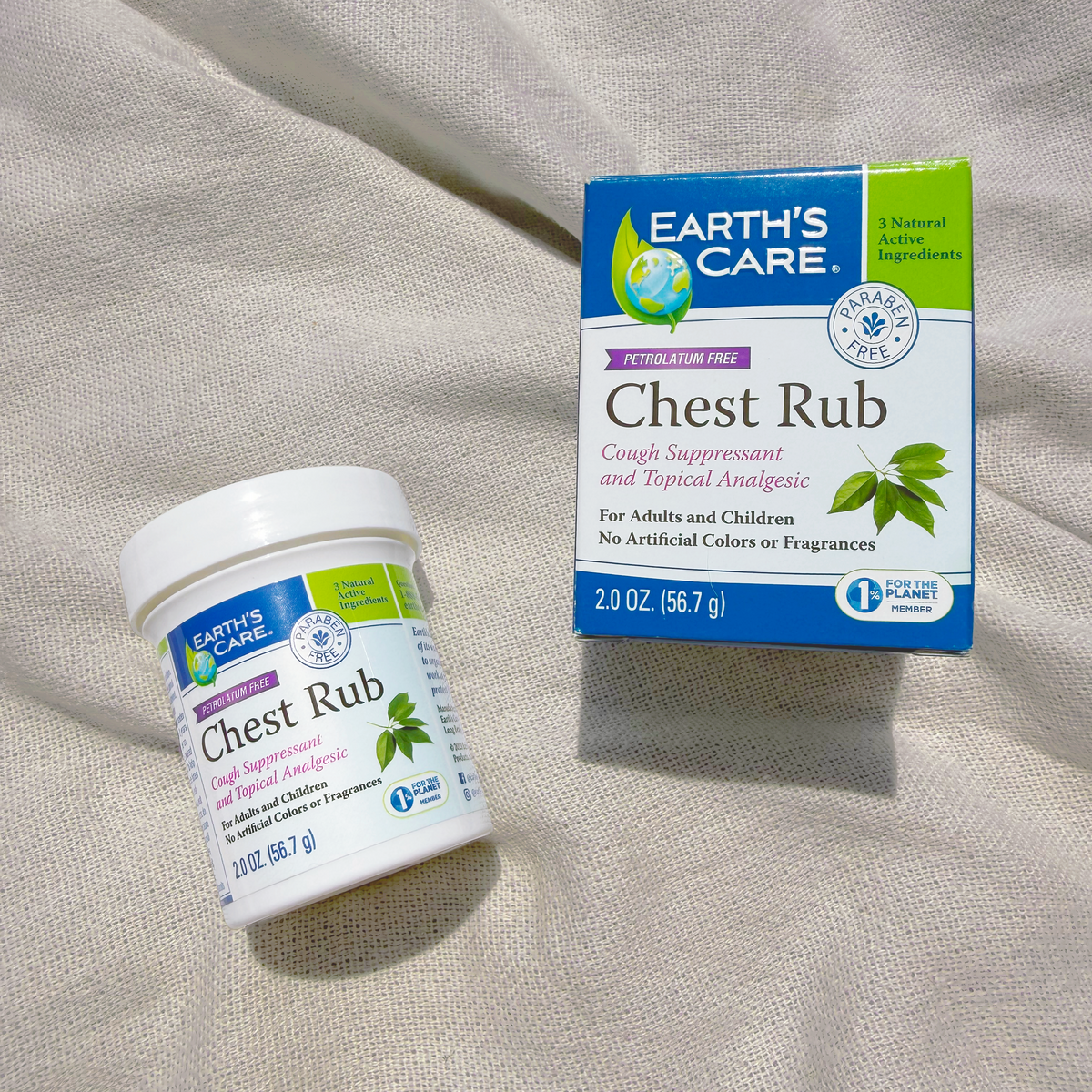 Earth's Care Chest Rub cough suppressant and topical analgesic shown as a white plastic jar with a white lid and a blue and green retail box, placed on a beige fabric surface.