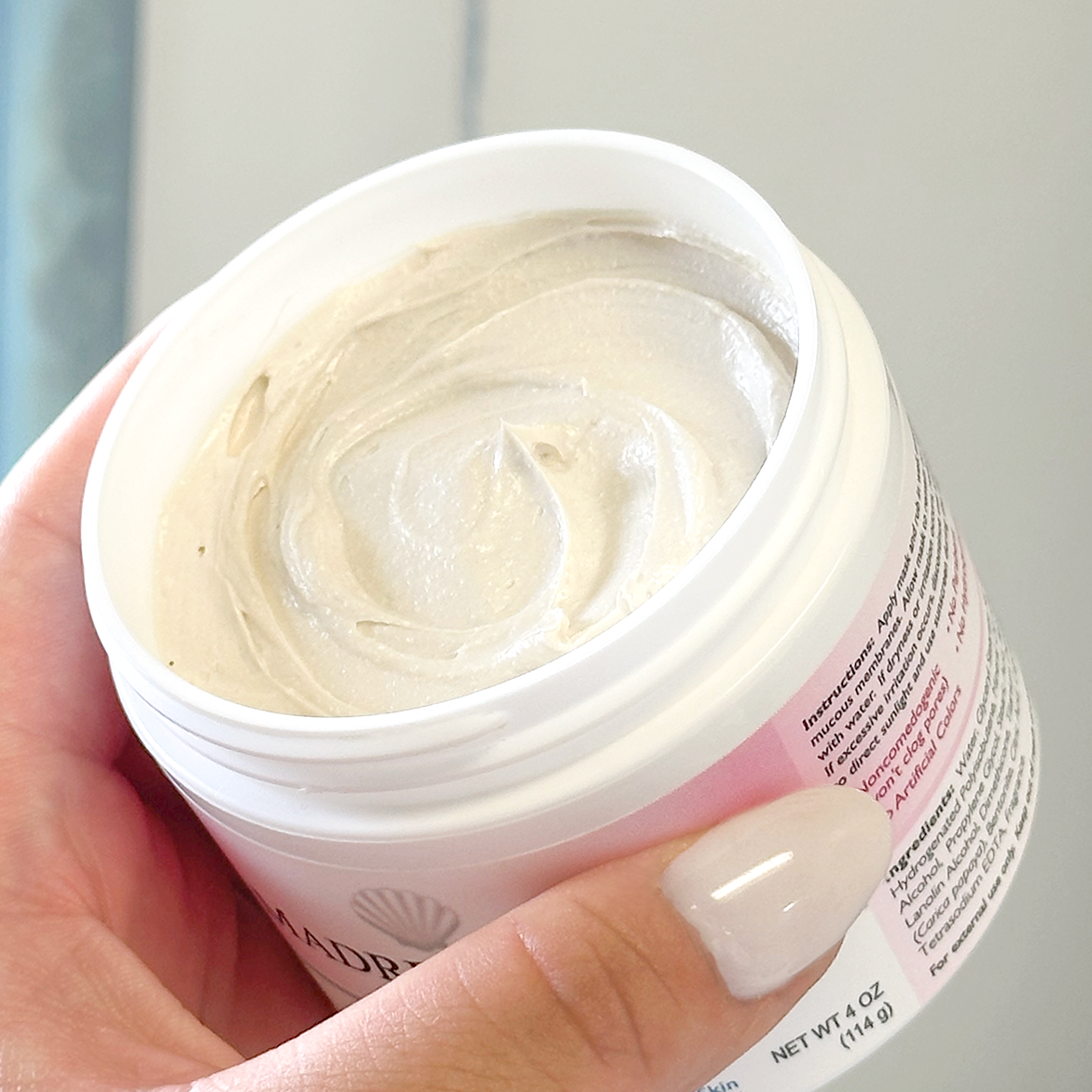 Hand holding jar of Madre Perla Maskwith shot of texture swirl. 